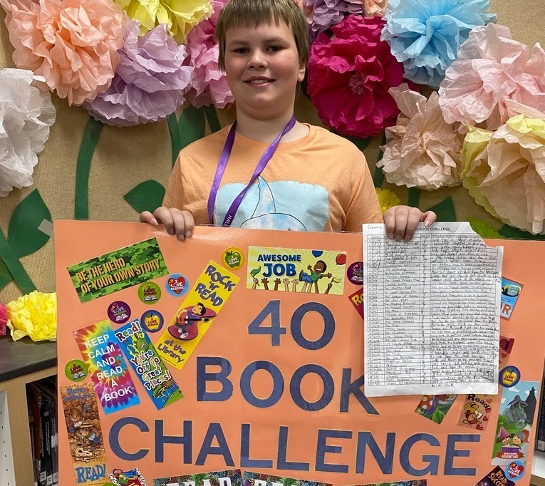 Student holding the 40 book challenge Poster