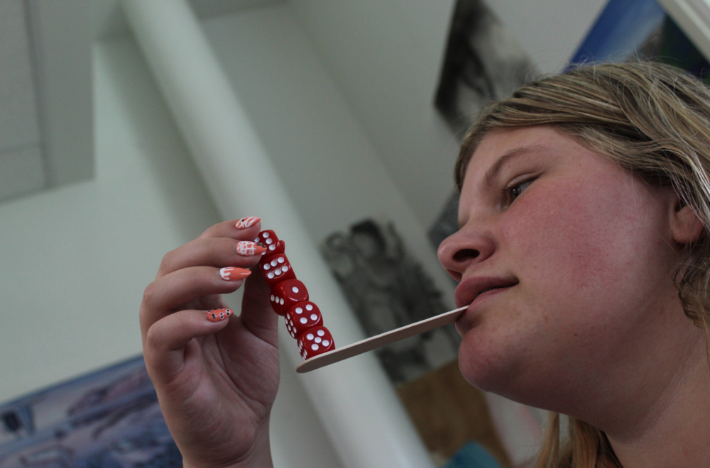 Student Balancing Dice on a popsicle stick in her mouth