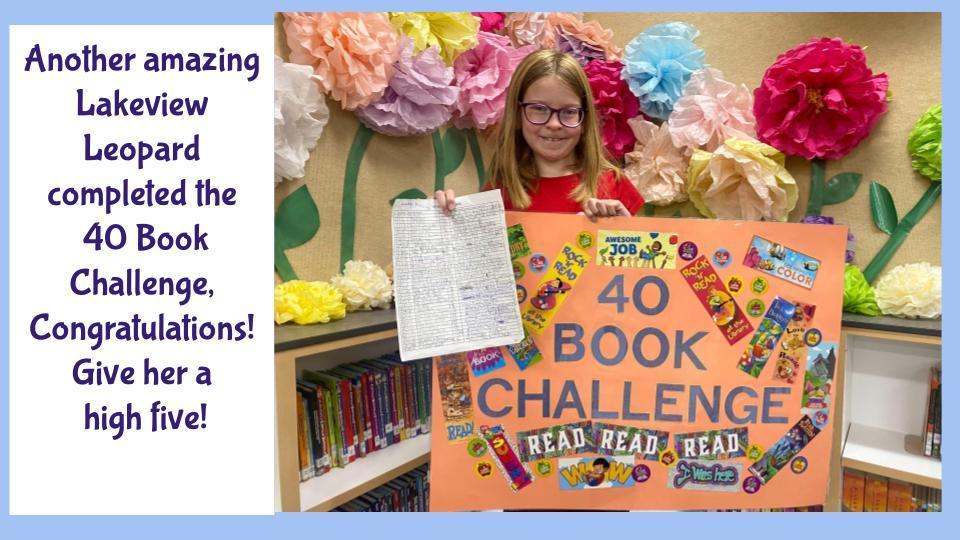 Student holding the 40 Book Challenge poster. Paper flowers in the background.
