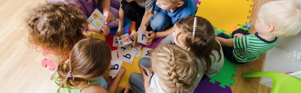 kinidergarten students gathered around letter cards