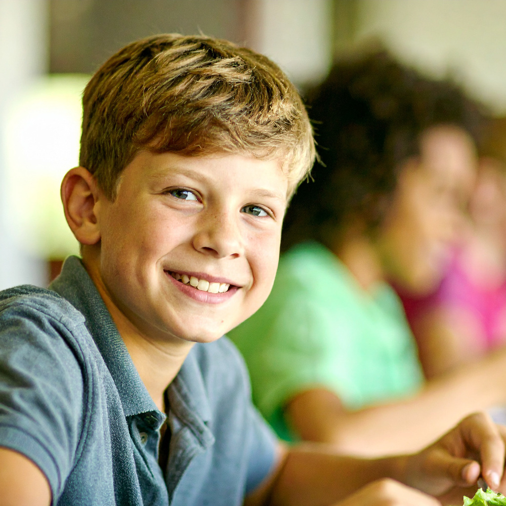 student smiling eating school lunch