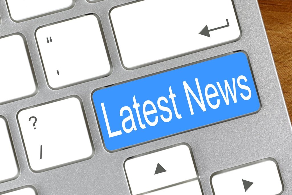 Close-up image of a computer keyboard with a bright blue key labeled “Latest News” replacing the usual key in that position. The keyboard is silver with white keys, and nearby keys include the enter key, question mark key, and arrow keys.