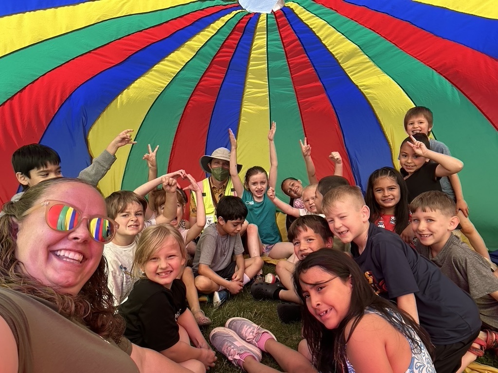 1st grade students under billowing colorful parachute