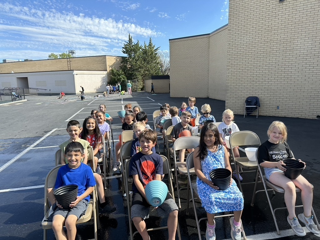 students lined up in chairs for a water relay race