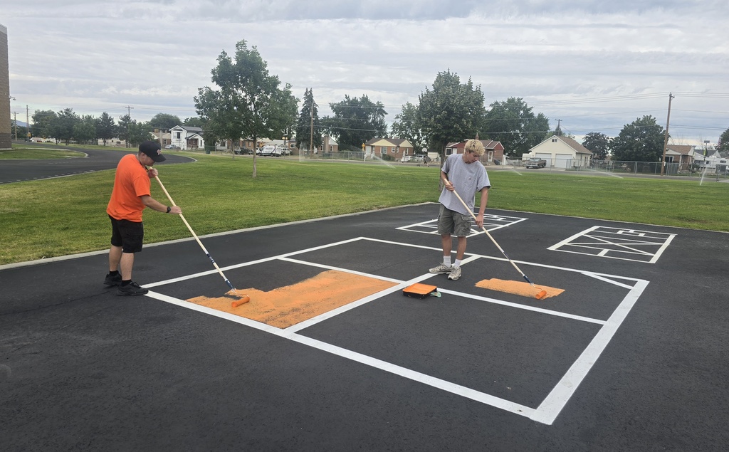 Two custodians painting squares on the blacktop
