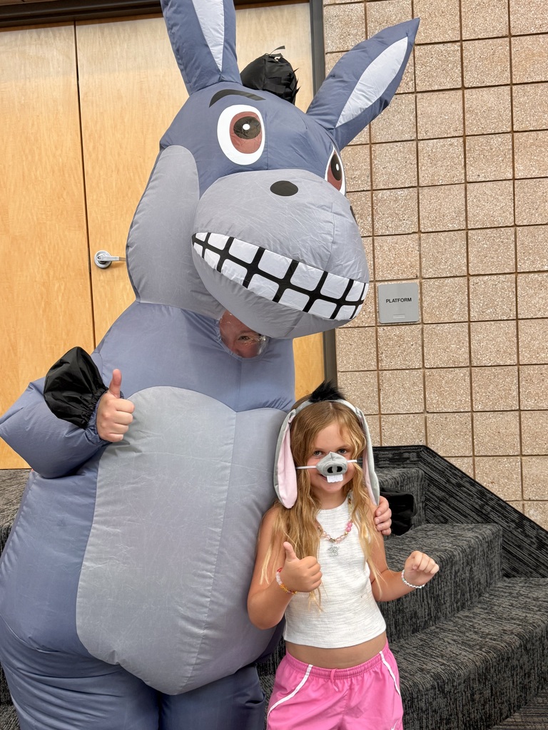student wearing a donkey nose and ears doing a thumbs up gesture, Miss G is also wearing a donkey costume and doing the same hand gesture 