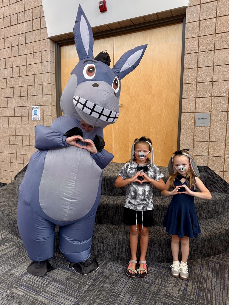 two students making hearts with their hands smiling in donkey costumes with Miss G who is also making this hand gesture and smiling in a donkey costume