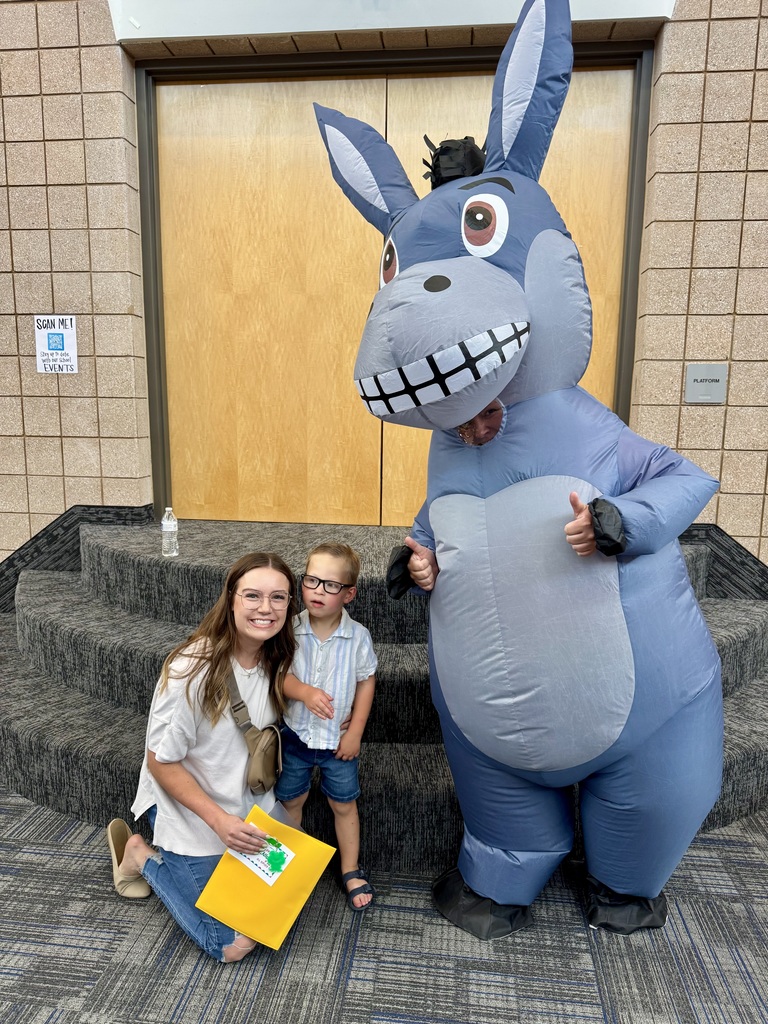 student and his mom smiling with Miss G in a donkey costume 