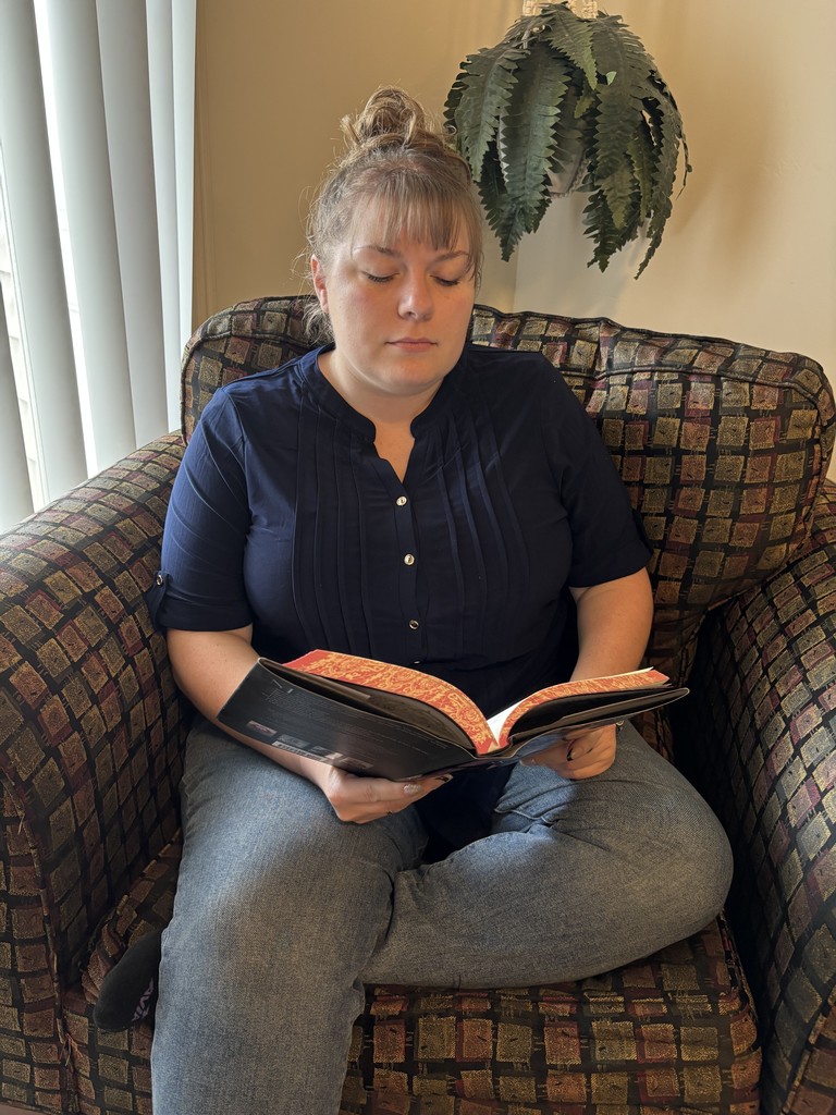 Mrs. Dalrymple in a chair reading a book
