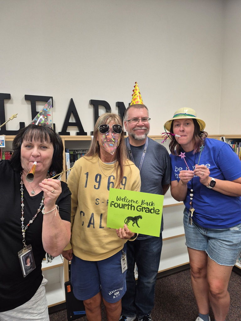 the fourth grade team wearing party hats and funny sunglasses and holding a "welcome back fourth grade" sign 
