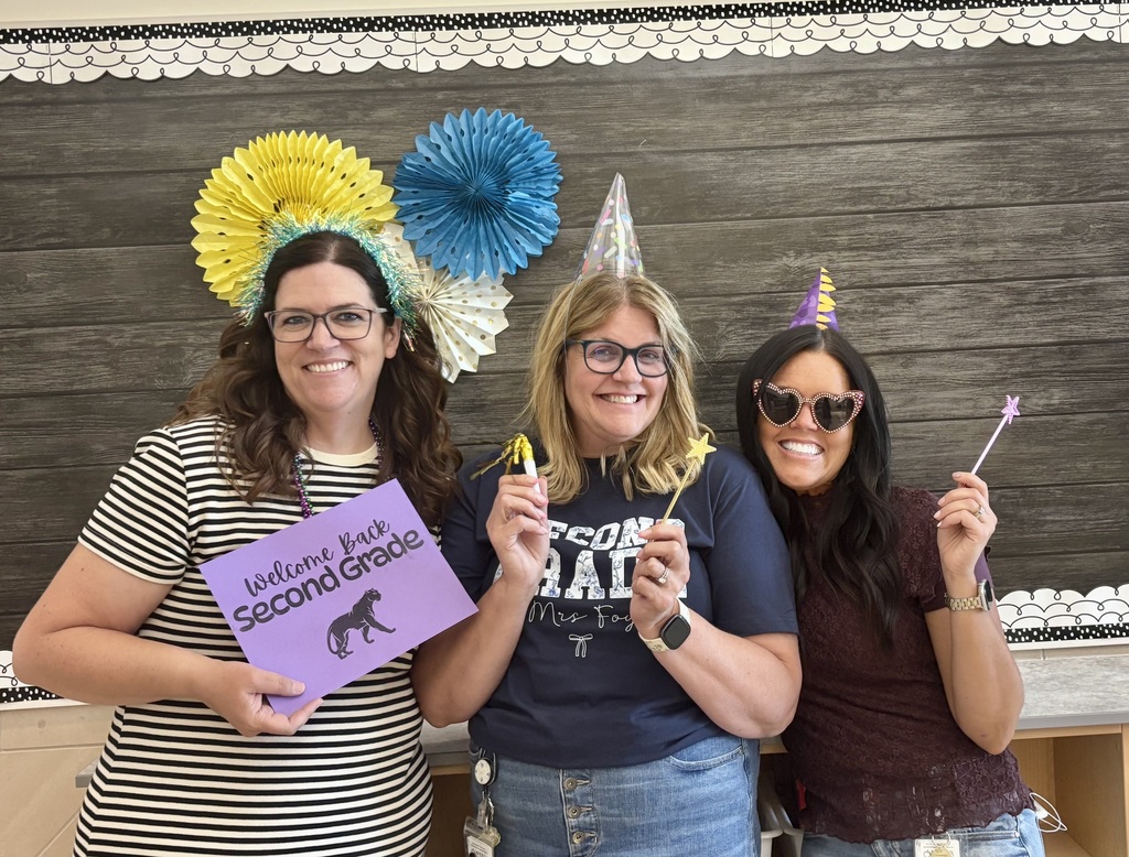 2nd grade teachers holding "welcome back second grade" sign. teachers are wearing sunglasses and hats