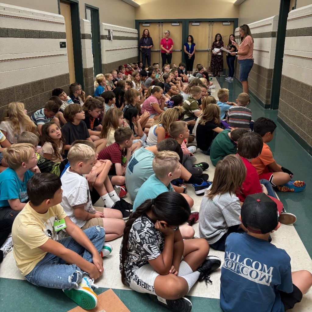 3rd graders listening to hallway procedures in the hall