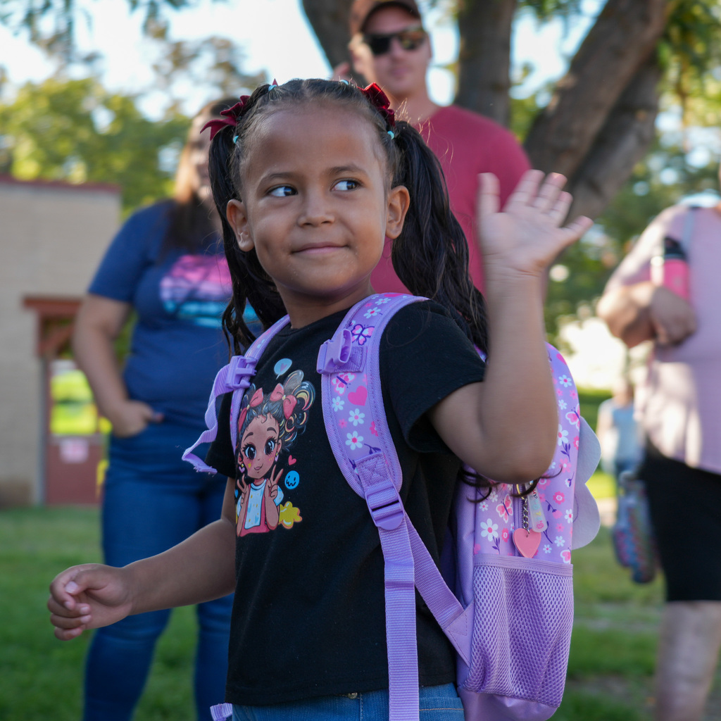 A child waves to her parents as she enters the building
