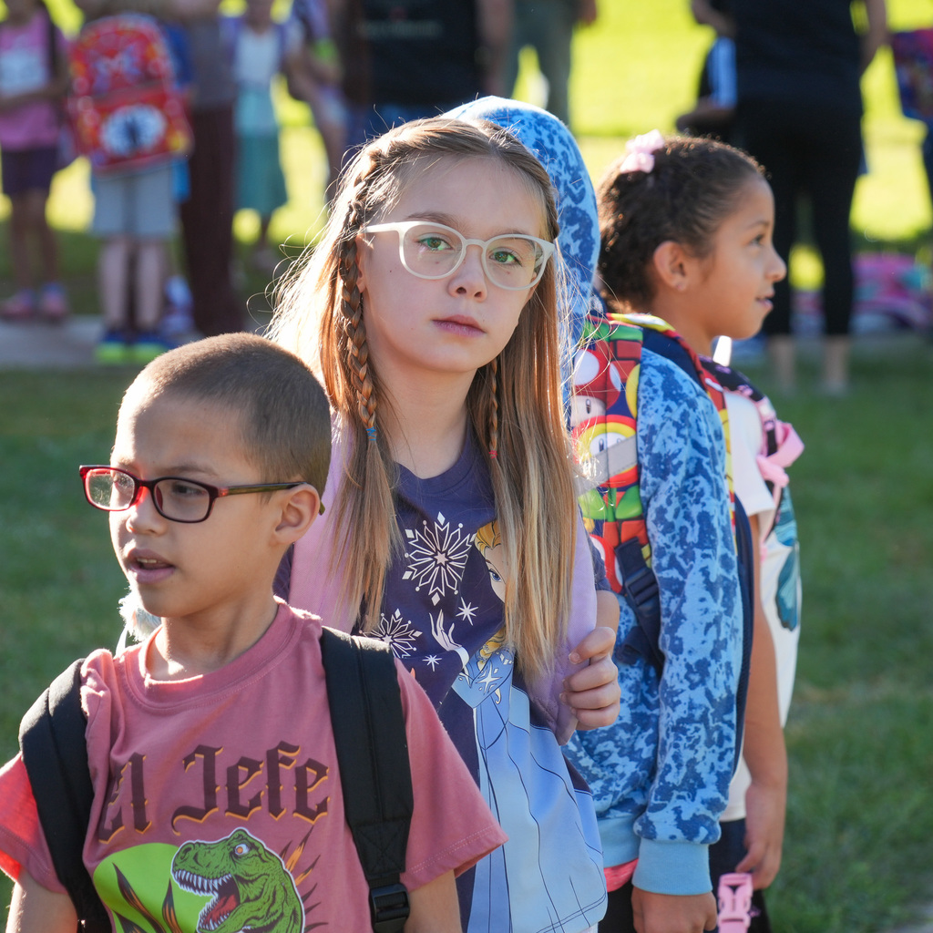 A group of elementary students waiting in line to enter school