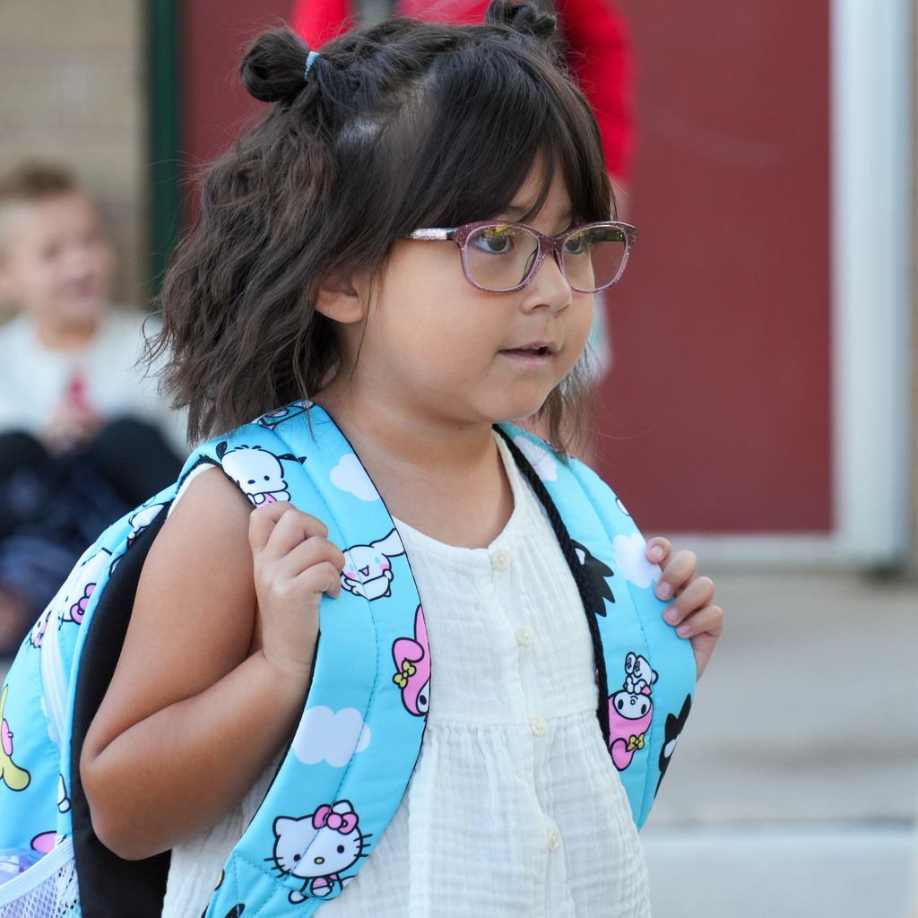 A kindergartner with her backpack on looking forward to school