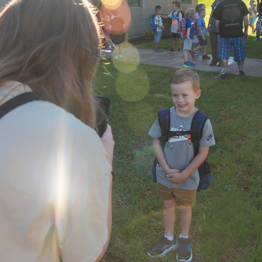 A mom taking a picture of her child in front of the school