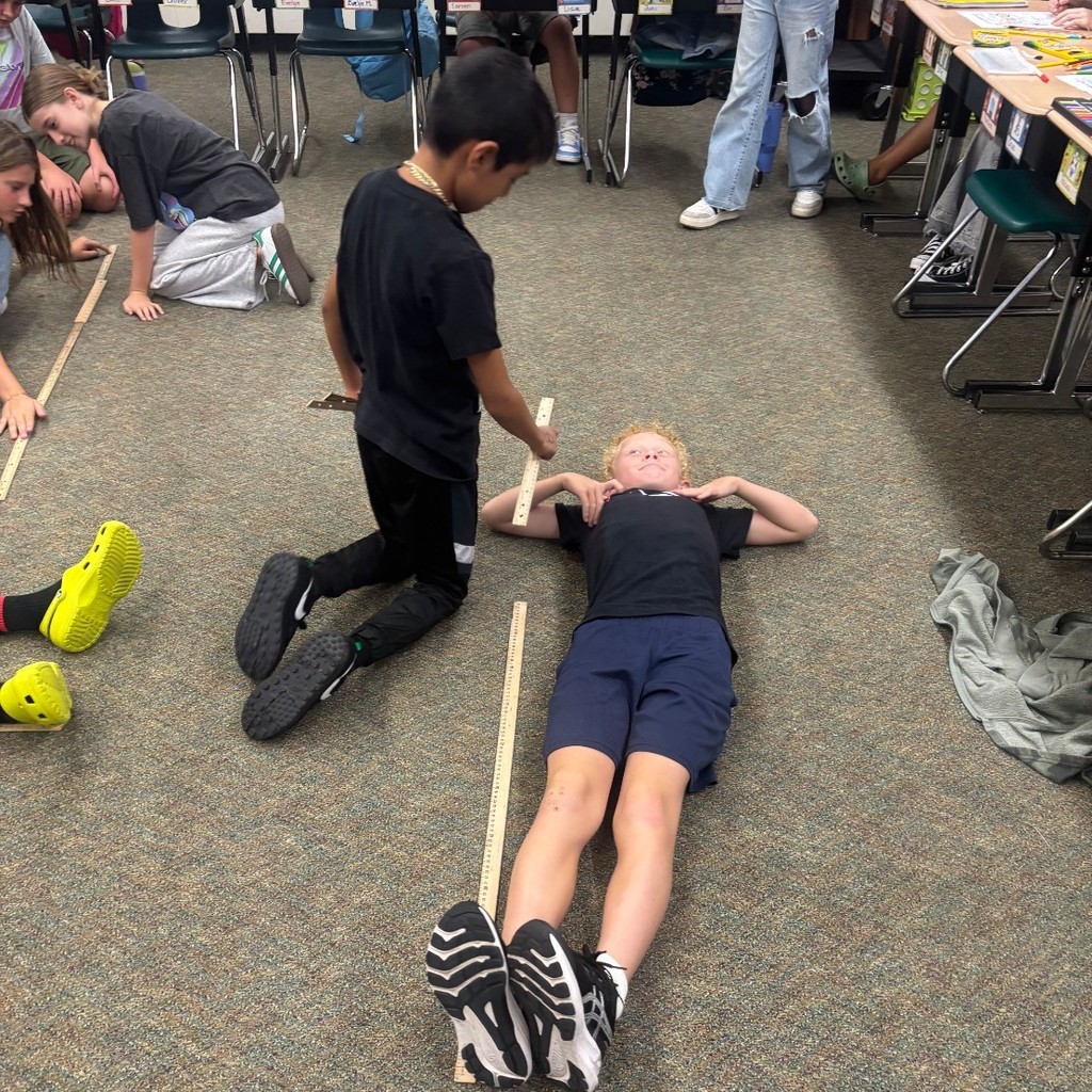 boys measuring each other's height in a classroom