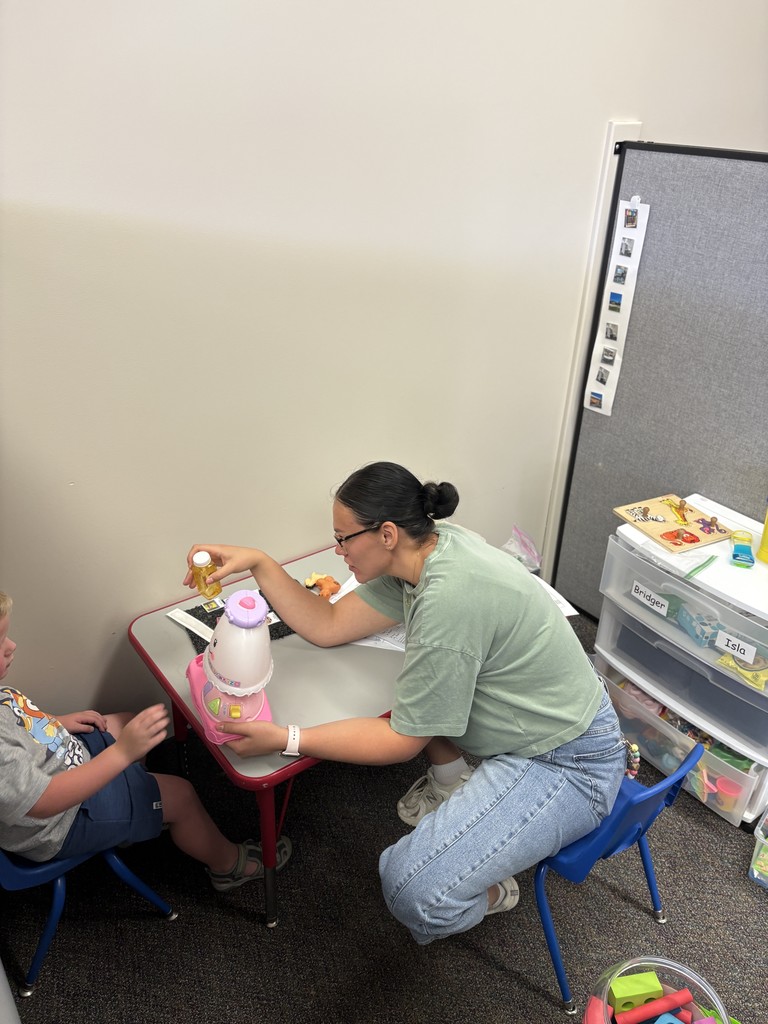 Jaymi working in a cubicle with a student