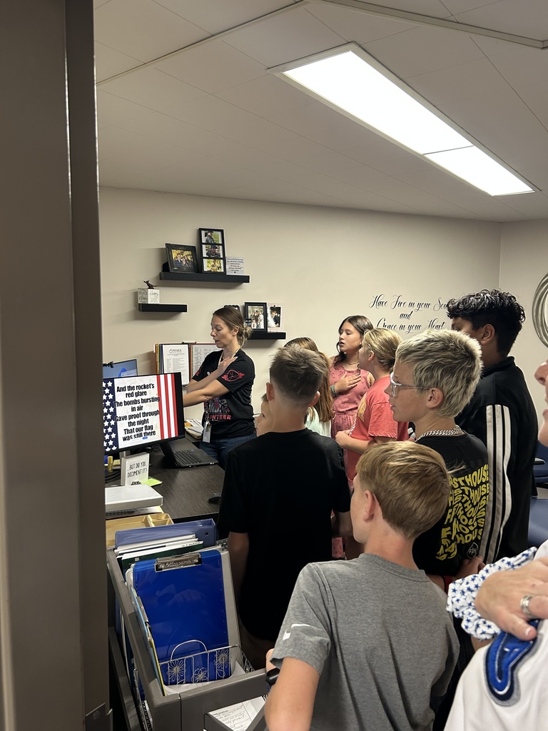 Students with their hand on their heart singing the National Anthem