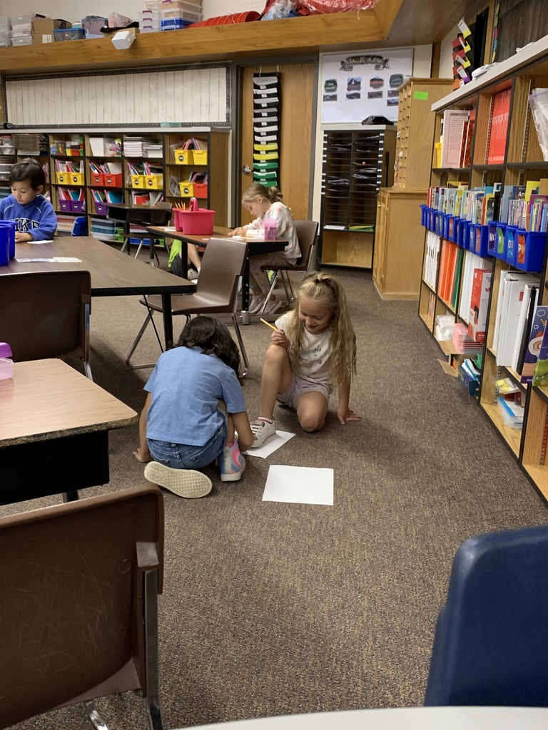 Helping each other trace the size of their feet.