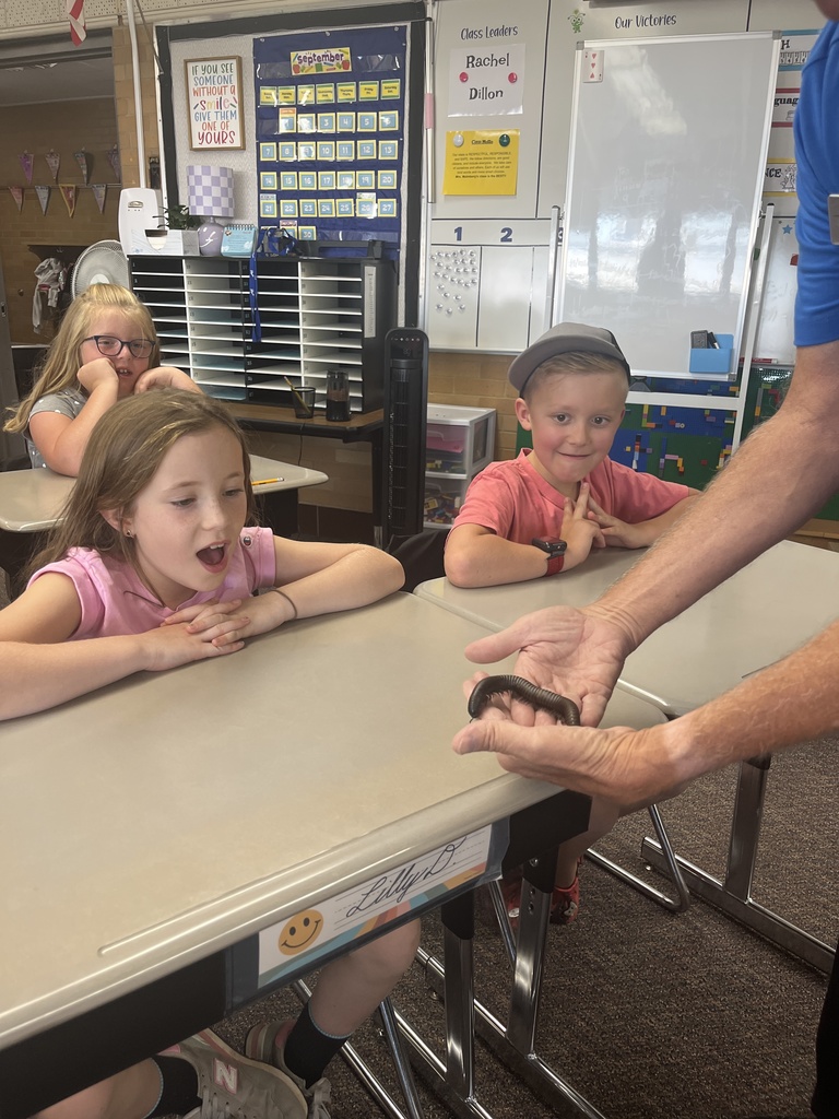 three students look in awe at insect held by aquarium employee