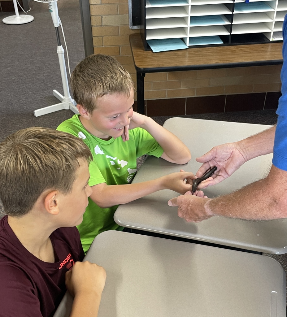 two students check out an insect held by the aquarium employee