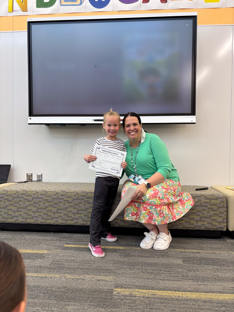 student holding award next to principal
