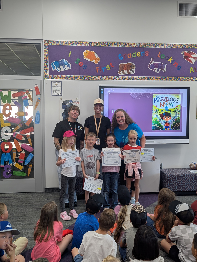 students holding awards next to teachers