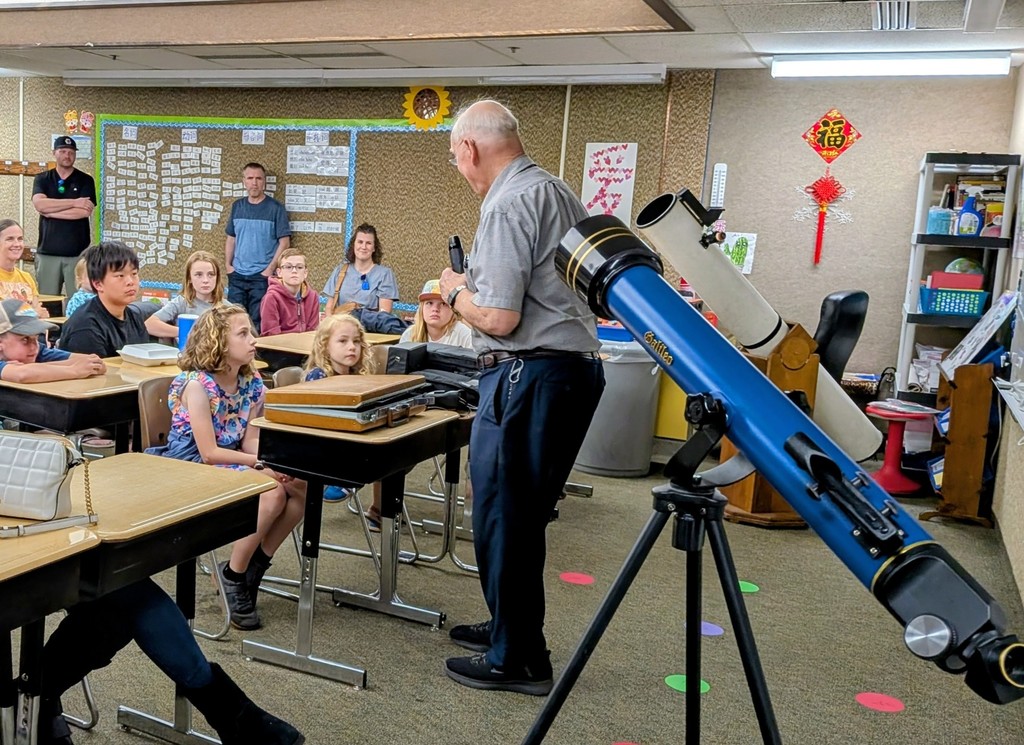 man with telescope teaching kids