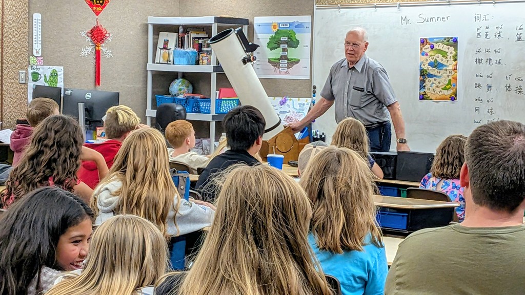 man with telescope teaching kids