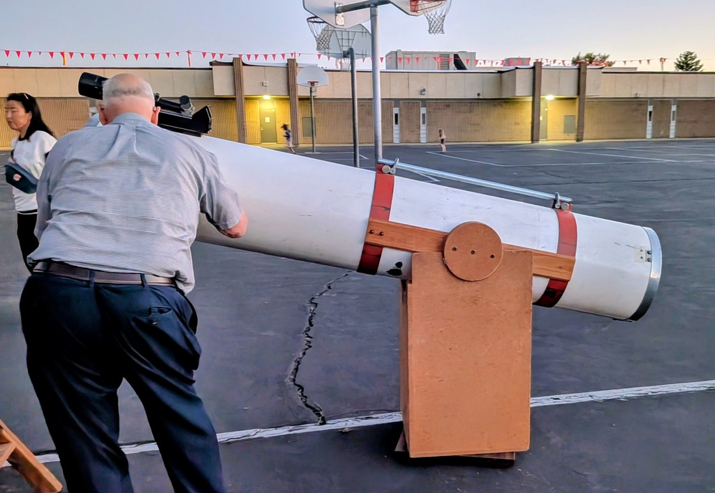 man with large homemade telescope