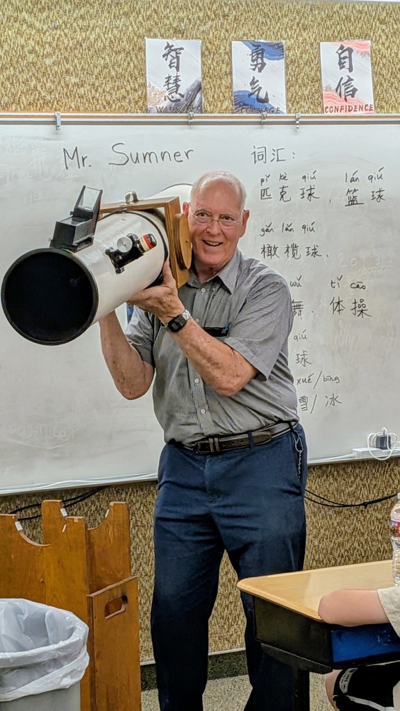 man holding up large homemade telescope