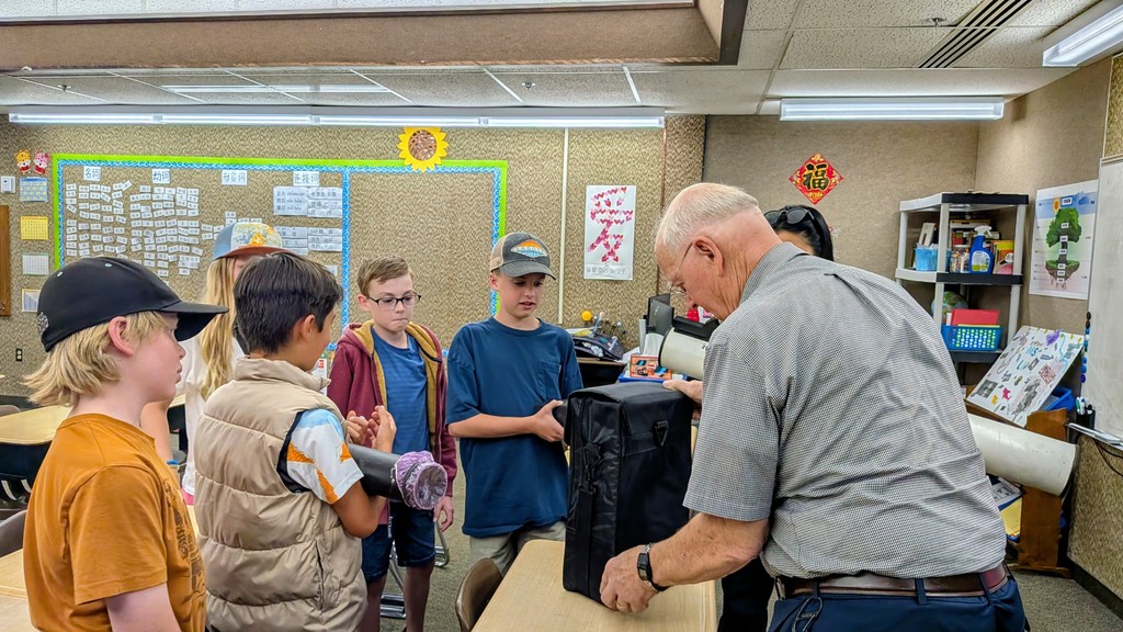 man showing students a telescope
