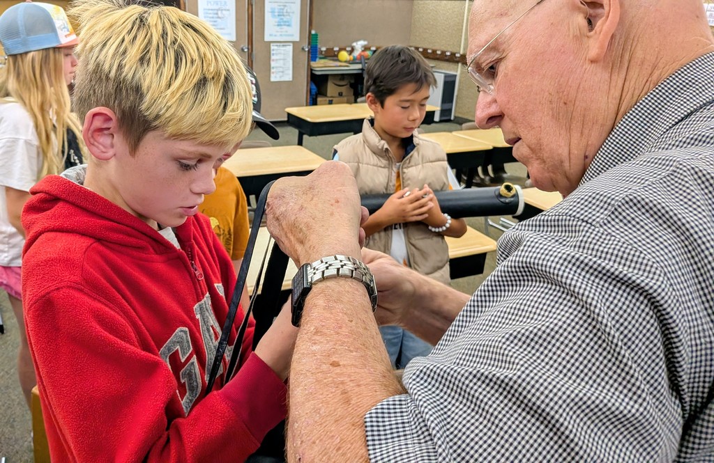 male student and an older man working together on a telescope