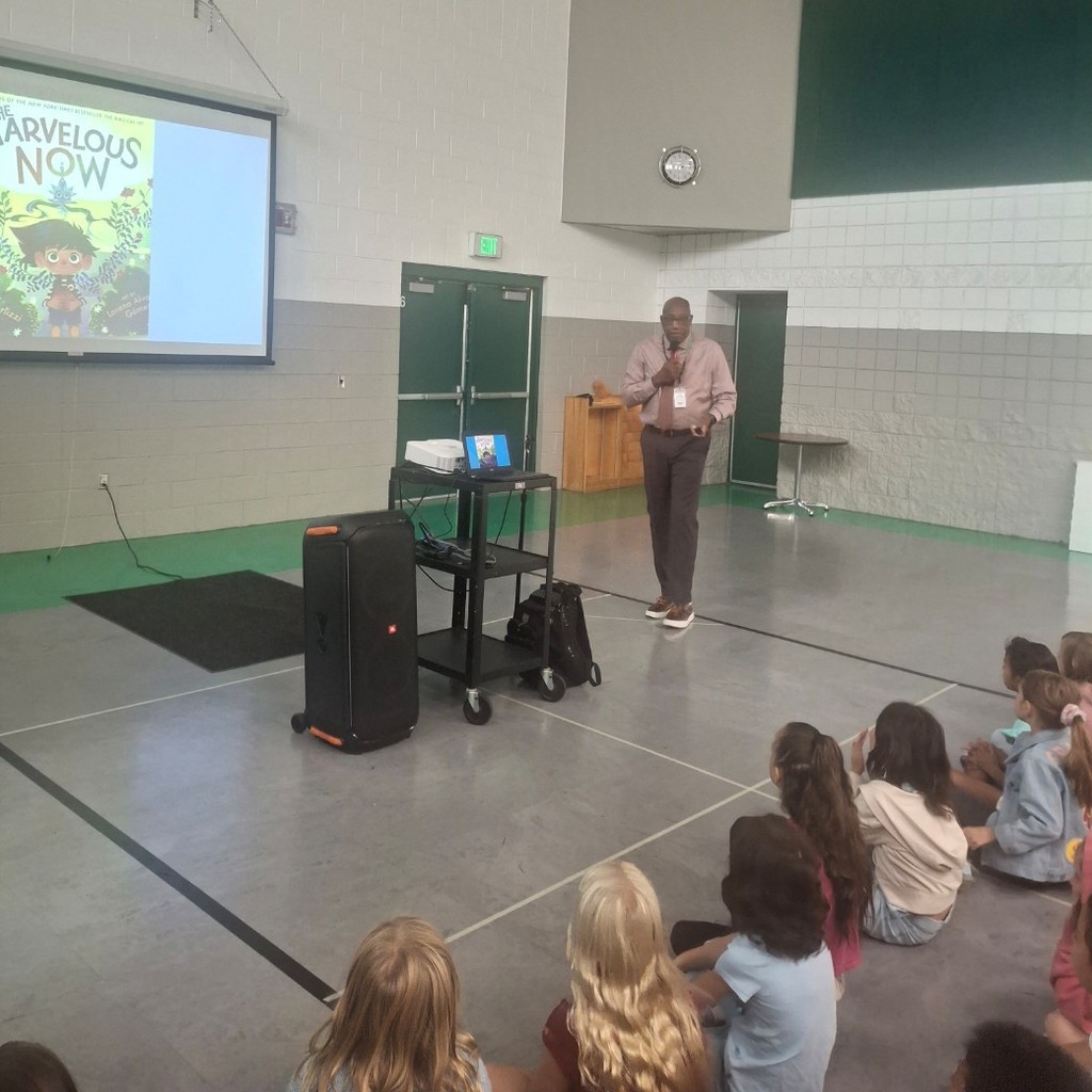 Superintendent Moore reading a book on a screen to students