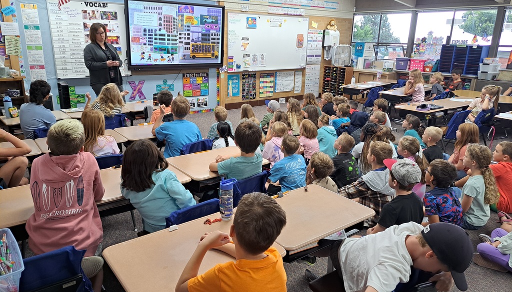 "Educators presenting to elementary school students in various classroom settings, with some using interactive displays."