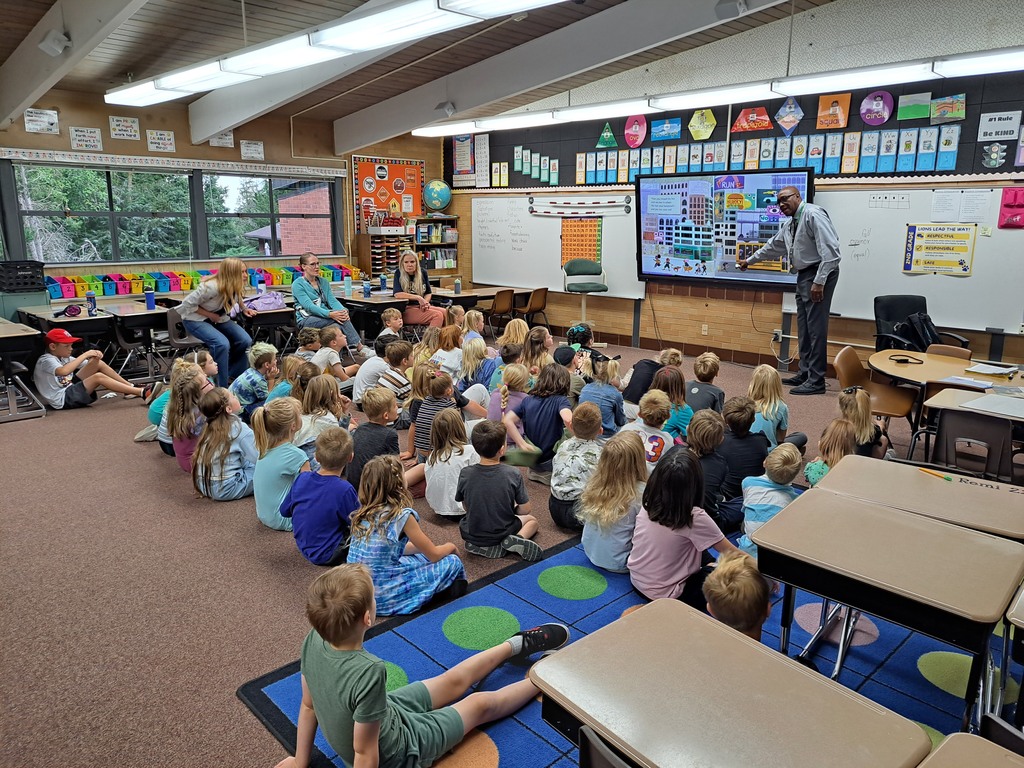 "Educators presenting to elementary school students in various classroom settings, with some using interactive displays."