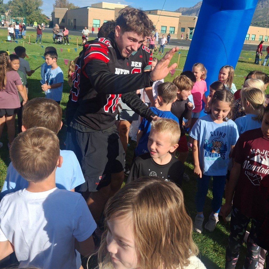 Kids at the fun run giving a high five to a Weber football player.