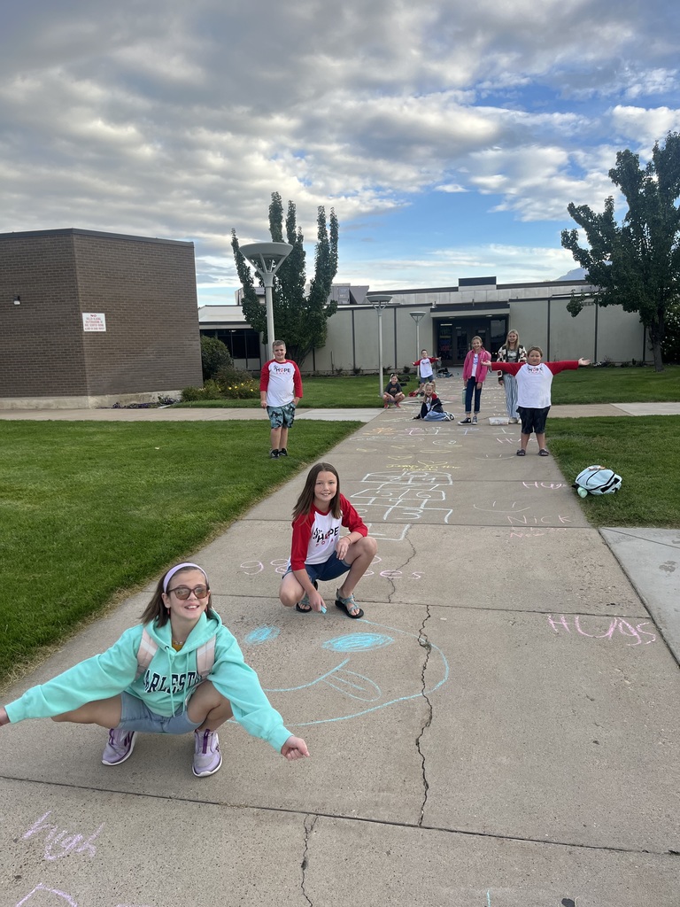 Kids smiling at the camera with their chalk art messages