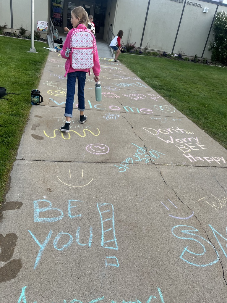Positive messages written on the sidewalk with chalk with students around