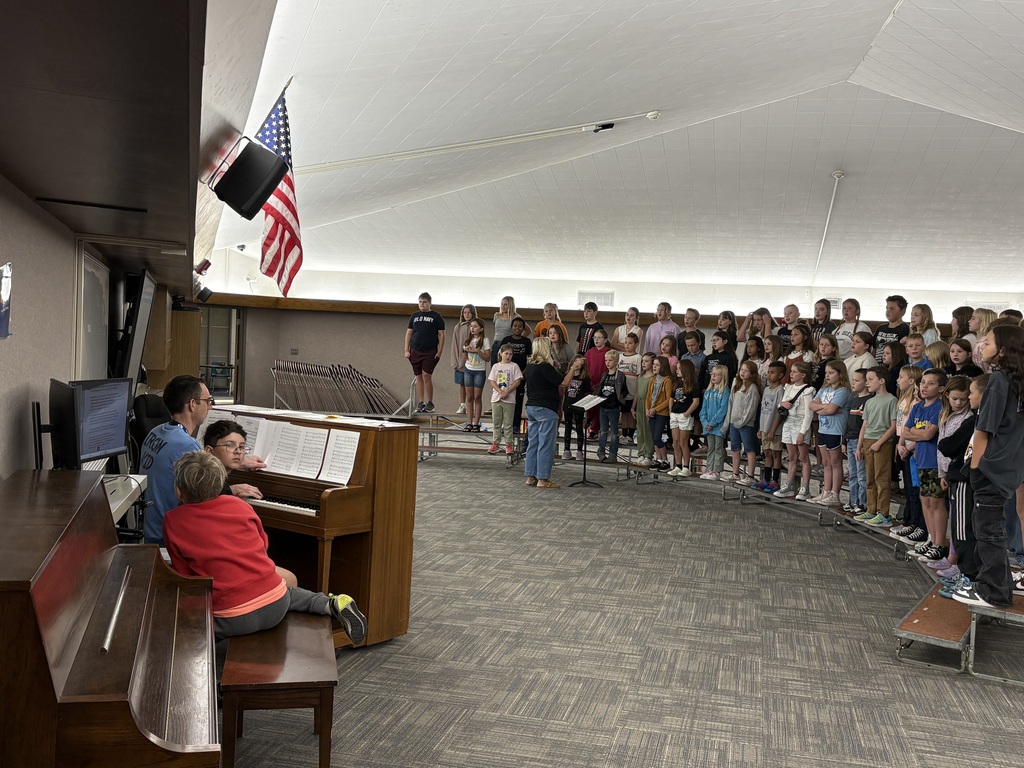 Students singing with teacher playing the piano