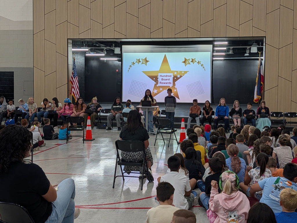 6th grade students standing in front of an auditorium presenting to the Roosevelt student body