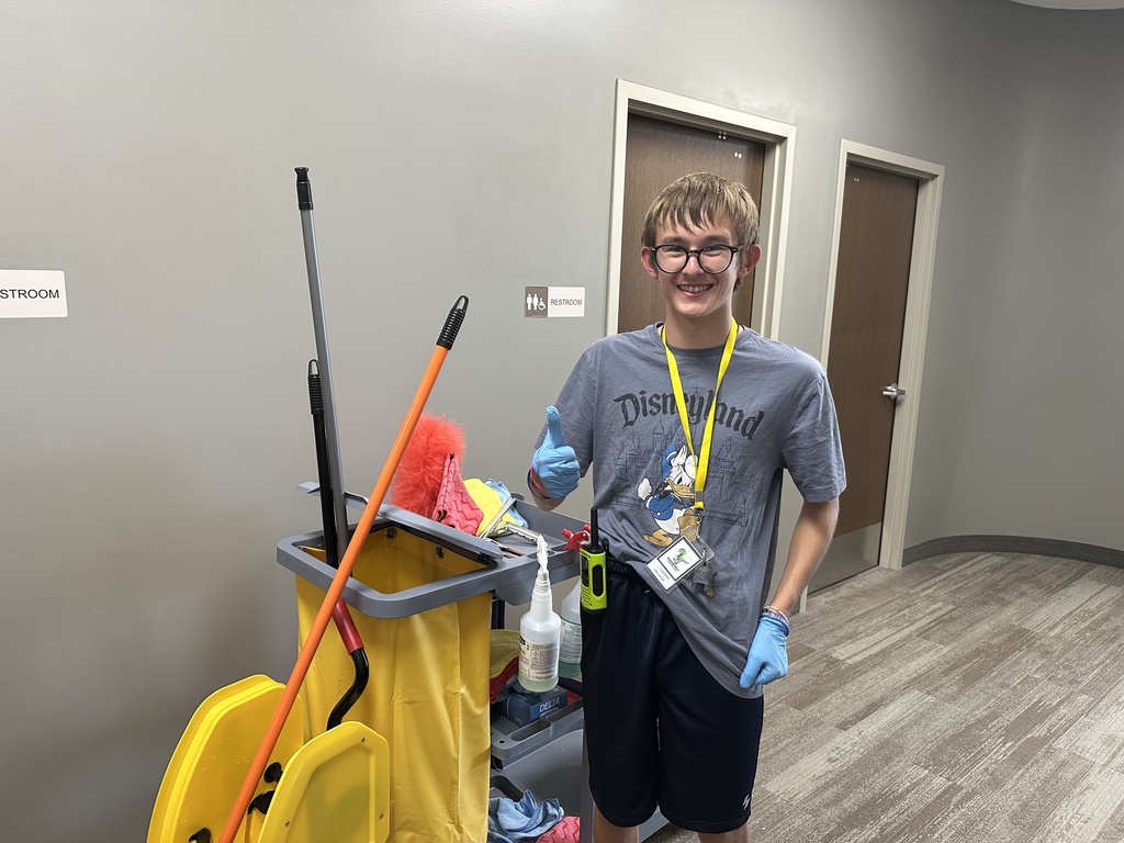 teenage custodian posing with his cleaning cart giving a thumbs up