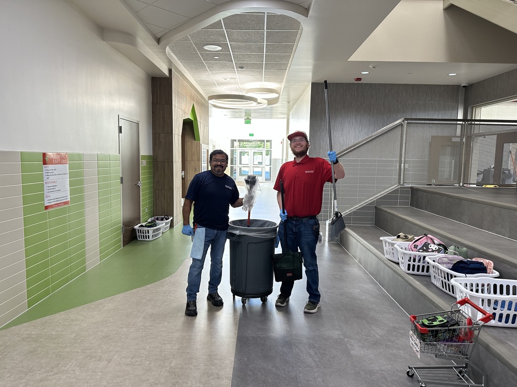two custodian standing in the hallway holding a broom and a plunger like a superhero
