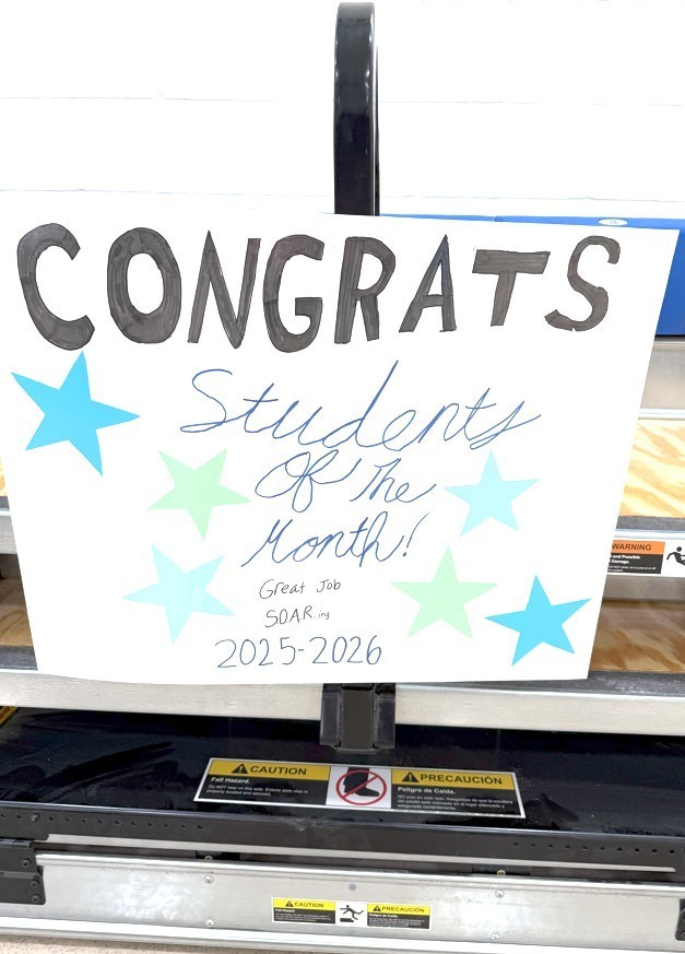 A close-up image of a hand-made sign that reads: CONGRATS Students of the Month! Great Job SOARing 2025-2026 with light blue and green stars decorating it.