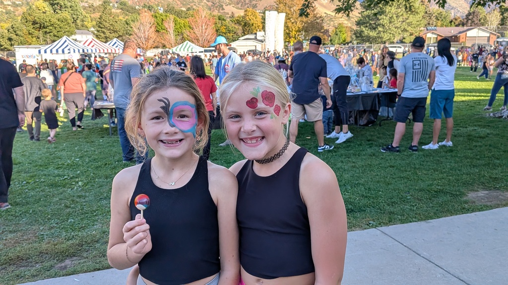 two girls in black tank tops eating lollipops at a carnival