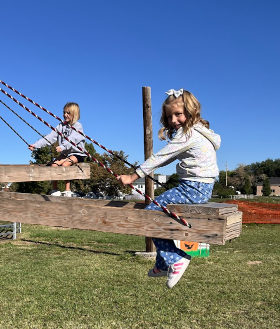 Student riding on rustic wooden swings,