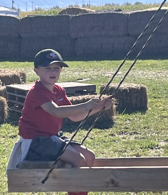 Student riding on rustic wooden swings,
