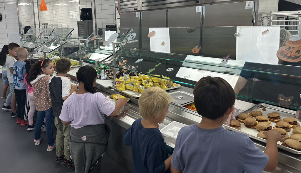 students walking past the serving area and putting lots of delicious looking food onto their trays
