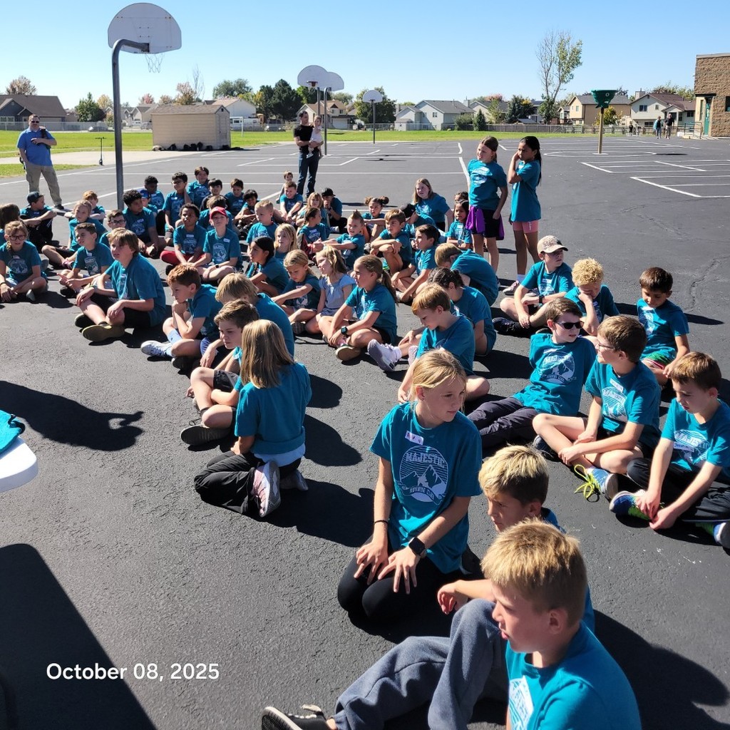 Kids in the running club sitting on the black top